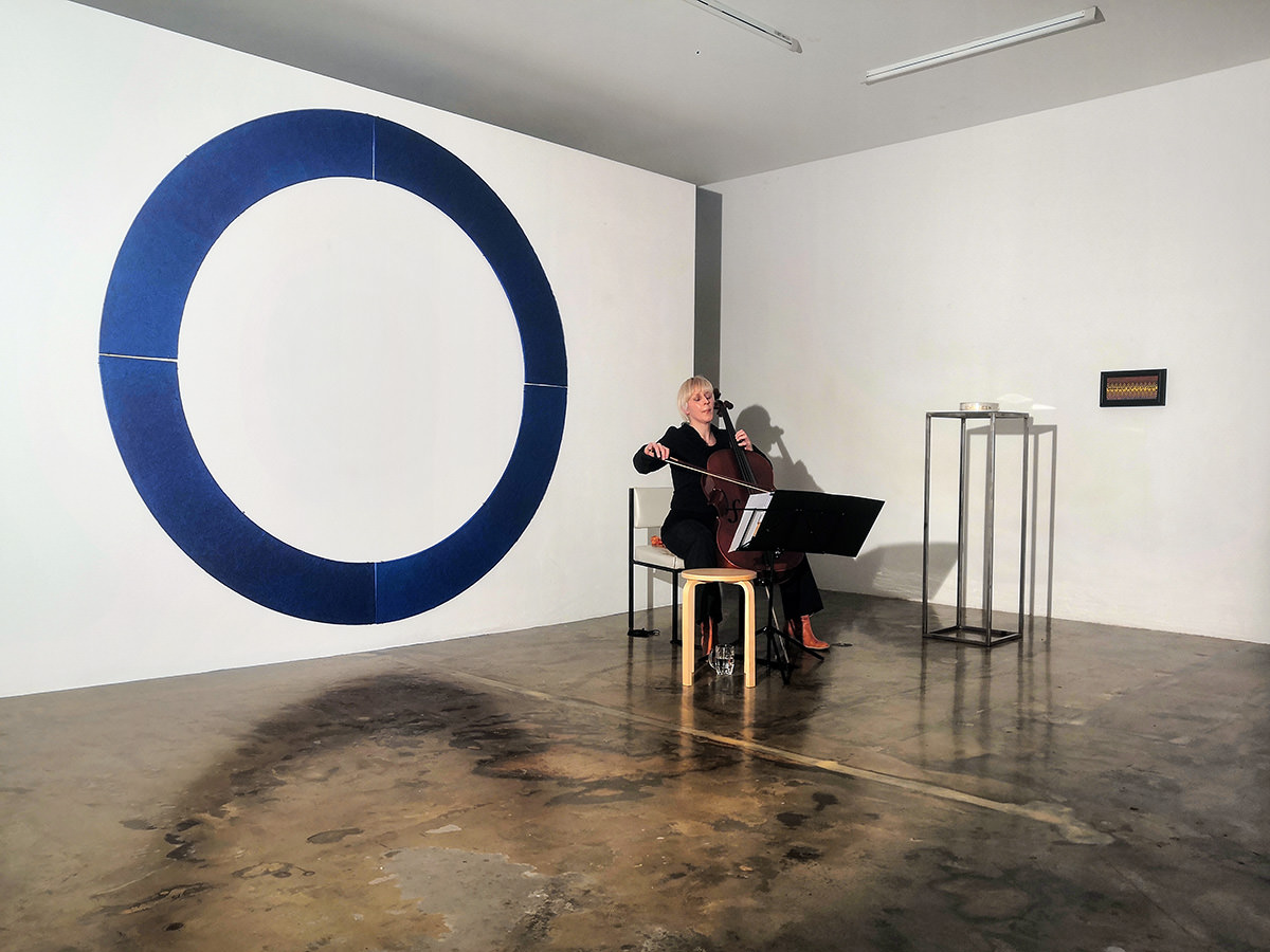 Violoncellospielerin vor einer Wand mit blauem Kreis